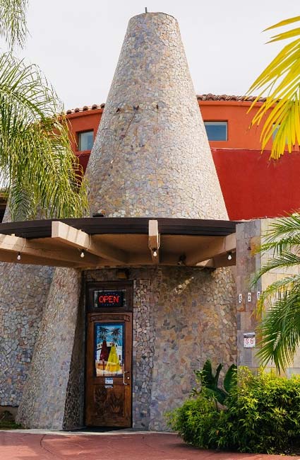 Stone cone-shaped building entrance with door, OPEN sign, plants; classic Escondido burritos.