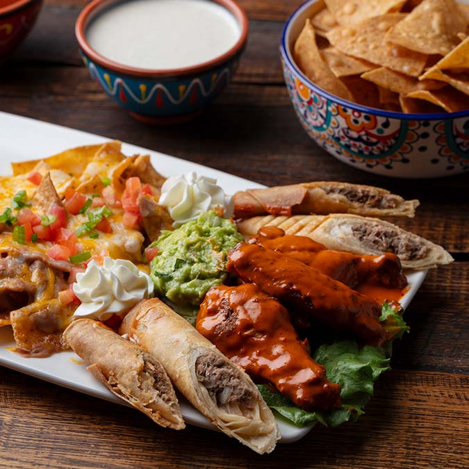 Assorted Mexican appetizers from a Mexican restaurant with chips, guacamole, and dipping sauce.