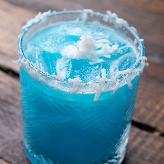 Blue cocktail with ice and coconut flakes, served Escondido-style at a lively Mexican restaurant.