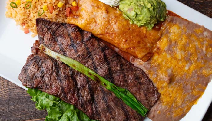 Enjoy classic Mexican food in Escondido: steak, enchilada, guacamole, rice, beans, and lettuce.