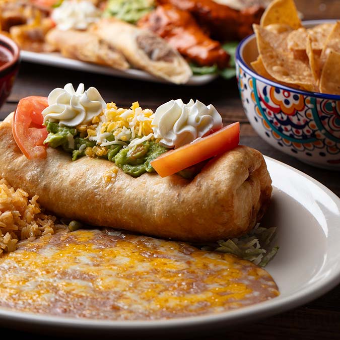 Enjoy a Mi Guadalajara Restaurant chimichanga with rice, beans, guacamole, and fresh tomato.