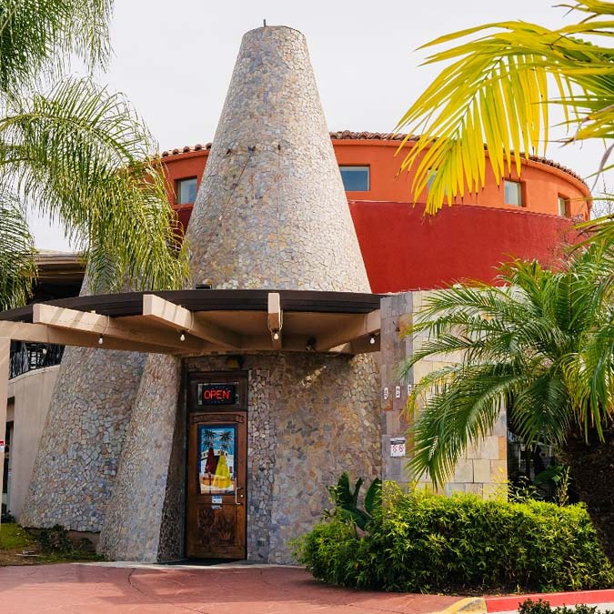 Stone cone-shaped building entrance with palm trees, OPEN sign, and Mexican Restaurant vibes.